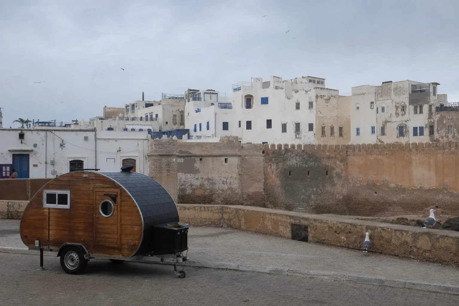Caravane teardrop garée près des remparts historiques d'Essaouira